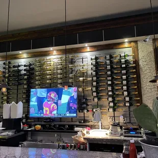 Wall of wine bottles and sports playing on the television at Wescafe in Alameda.