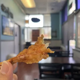 a hand holding a piece of fish and chips