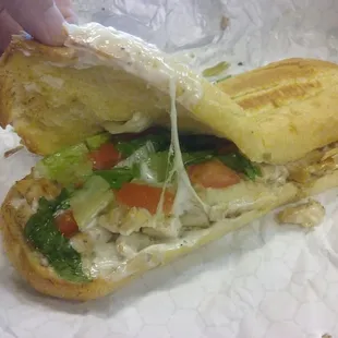 Grilled chicken sandwich with lettuce, tomato and white sauce.