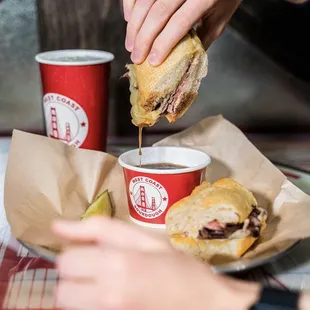 a person dipping a sandwich into a cup of coffee