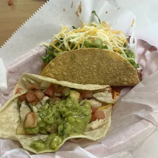 Chicken taco with guacamole and a ground beef taco.