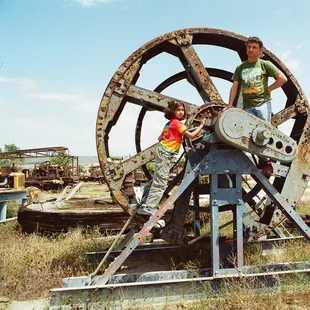 Me posing on a large wheel at West Kern Oil Museum.  I am wearing T-shirt from San Francisco Mime Troupe.
