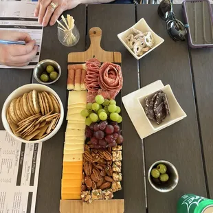 a platter of cheese, crackers, and grapes