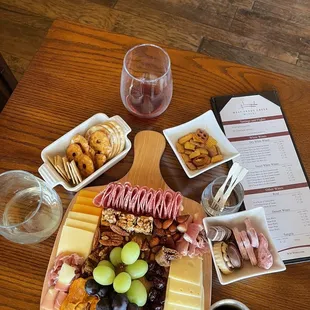 a platter of cheese, meat, grapes, and crackers