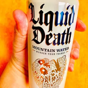 a hand holding a can of liquid death