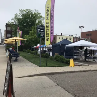 a sidewalk with tables and umbrellas