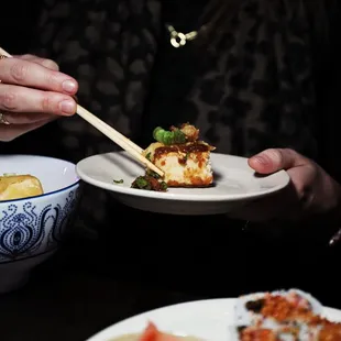 a woman holding chopsticks over a plate of food