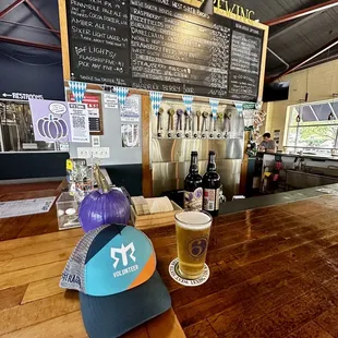 a glass of beer and a hat on a bar