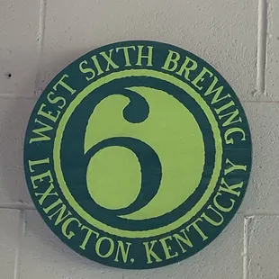 a green and black sign on a white brick wall