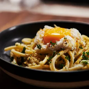 a plate of pasta with an egg on top