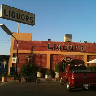 a red truck parked in front of a liquor store