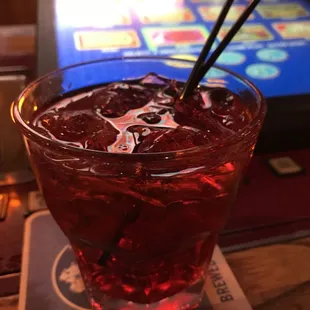 a glass of red drink on a coaster