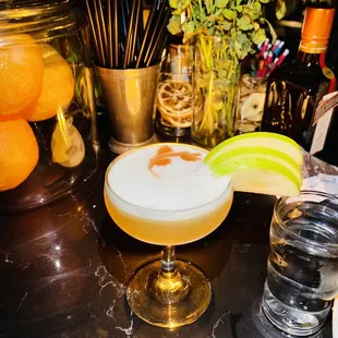 a cocktail in a coupe glass with a lime slice