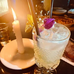 a glass of alcohol with a candle in the background