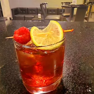 a glass of tea with lemon and raspberry garnish