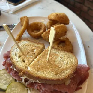a ham sandwich with pickles and onion rings