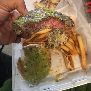 a hand holding a sandwich and french fries