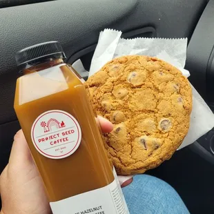 a person holding a cookie and a bottle of juice
