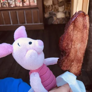 a person holding a stuffed pig and bacon