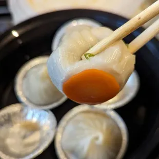 Soup dumpling with a cute slice of carrot on bottom to prevent them from sticking to the aluminum cup.