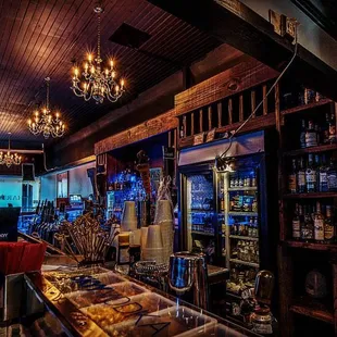 the inside of a restaurant with a bar and a chandelier