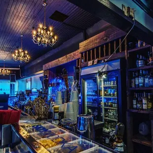 the inside of a restaurant with a bar and a chandelier