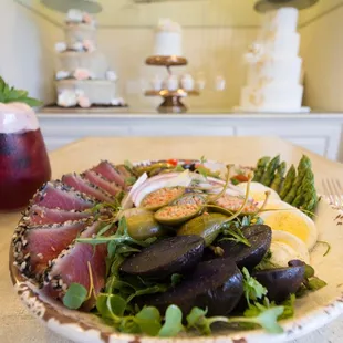 Nicoise  organic mixed greens, tomatoes, pee wee potatoes, nicoise olives, red onions, asparagus, caper berries, hard-boiled eggs, Ahi