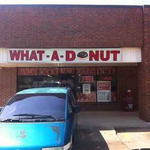 ows a blue car parked in front of a donut shop