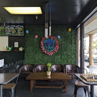 Seating arrangements, a chess board set up at a window table, and a "green" wall with a backlit shop logo.