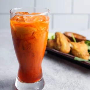 a glass of cold beverage and a plate of fried chicken wings