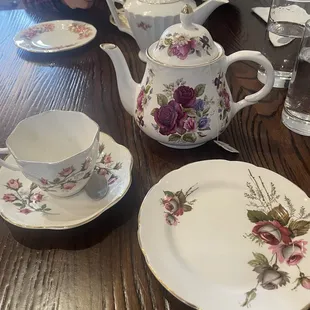 a person sitting at a table with a tea pot and tea cups