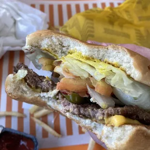 a hand holding a hamburger with pickles and onions