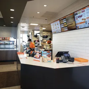 a restaurant counter with a menu on the wall