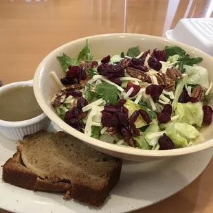 Very fresh salad with vinaigrette salad dressing with a small slice of apple spiced quick bread.