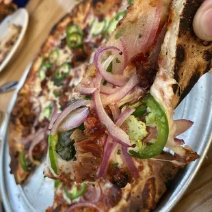 a person taking a slice of pizza