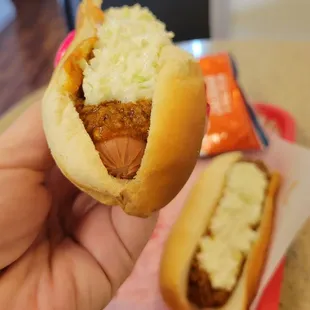 a hand holding a hot dog with coleslaw