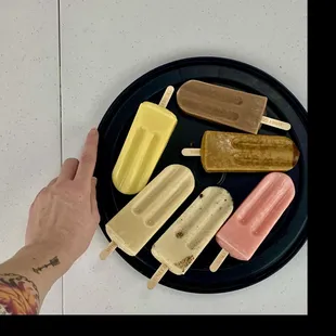 a person holding a plate of ice cream pops