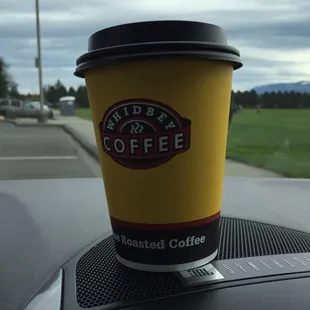 a cup of coffee on the dashboard of a car