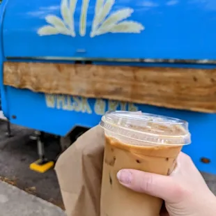 a hand holding a cup of iced coffee