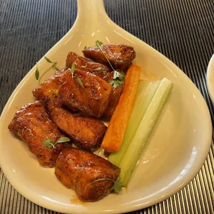 a platter of chicken wings, carrots and celery