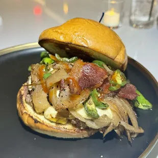 WDCW burger with whisky onion, bacon, jalapeño, shishito, spicy cheese, bleu cheese, cheddar, and sriracha