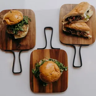 three sandwiches on wooden cutting boards