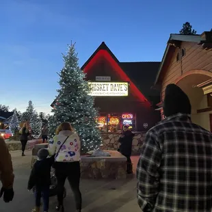 people walking in front of a christmas tree