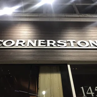 a corner store sign lit up at night