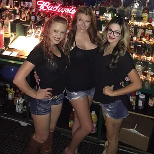 three women standing in front of a bar