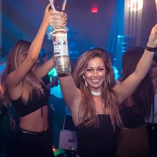 a woman holding a bottle in the air
