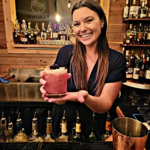 a woman holding a cocktail in a bar