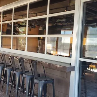 a row of bar stools in front of a window