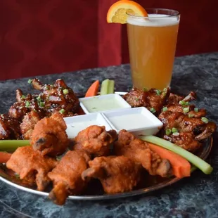 a plate of chicken wings, carrots, celery, celery, and a glass of