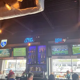 people sitting at a bar watching tvs